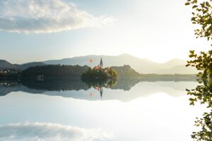 Island church and castle reflected in calm lake at sunrise